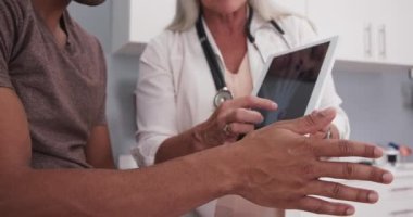 Doktor X-ray 'i tablette gösterirken yaralı el ve bileği tutan siyahi hastaya yakın çekim. Doktorun röntgenini ve erkek hastaya olan ağrısını açıklamaya yaklaş.