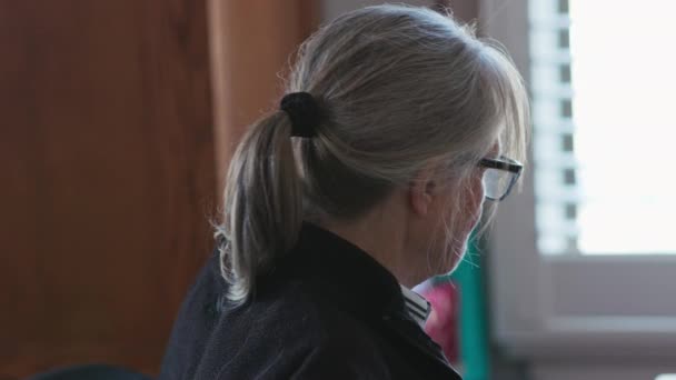 自宅の事務所で働いていた白人上級女性 彼女の机の上の書類を通して見ている高齢者の白い女性のハンドヘルド側のビュー スローモーション4K — ストック動画