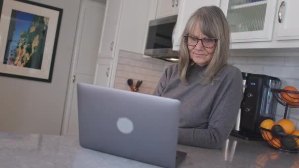 Üst Düzey Beyaz Kadın Mutfaktaki Dizüstü Bilgisayarda Postaları Kontrol Ediyor — Stok video