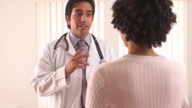 Meksikalı doktor Afrikalı Amerikalı hastayla konuşuyor.