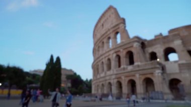 Roma İtalya 'da antik kolezyumun önünde yürüyen insanlar. Turistlerin Avrupa 'nın eski kentindeki tarihi anıtın etrafındaki araziyi keşfetmelerine odaklanmış bir bakış açısı