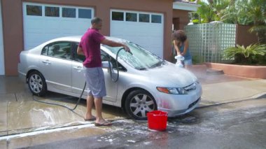 Garaj yolunda araba yıkayan çift.
