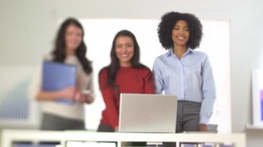 Üç iş kadını kameraya gülümsüyor.