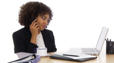 İş kadını cep telefonuyla masada oturuyor.