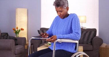 Tablet ile tekerlekli sandalyede oturan olgun Afrika kadın