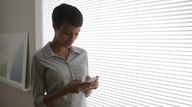 Siyah iş kadını cep telefonuyla mesajlaşıyor.