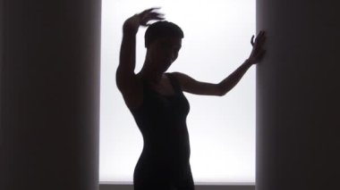 Parlak ışığın önünde dans eden Afrikalı Amerikalı kadının yan görüntüsü