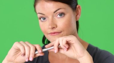 Elinde kalem tutan genç bir kadının yakın plan portresi.