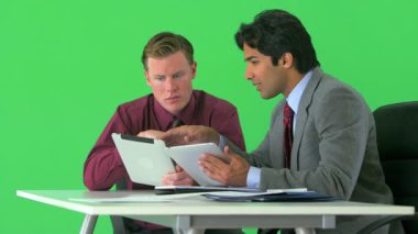 Yeşil ekranda tabletlerle çalışan iki işadamı