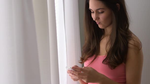 年轻的白人女人透过窗户发短信 — 图库视频影像