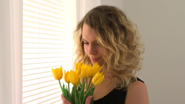 Blondynka Stojąca Przy Oknie Bukietem Tulipanów — Wideo stockowe