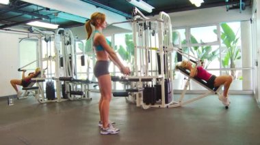 Çömelme hareketleri yapan, ağırlık kaldıran kadınlar.