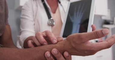 Erkek hasta el ve el bileği x ışını tablete açıklayan doktor ile kapatın. X-ışını hastalar bilek ve el ile elektronik pad tutan kıdemli doktor sıkı görünümü
