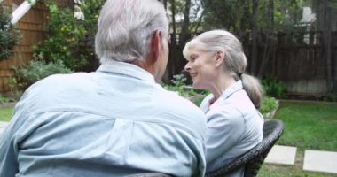 Yaşlı çift bahçede konuşuyor ve oturuyor.