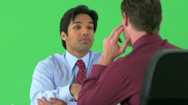 Yeşil ekranda konuşan iki iş adamının omzunun üstünden.