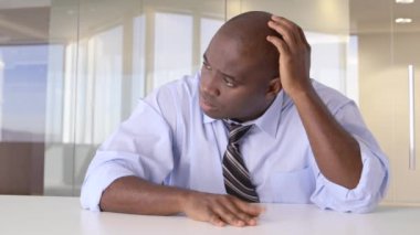 Afrika kökenli Amerikalı iş adamı masada düşünüyor.