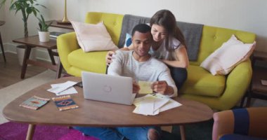 Çekici genç Afrikalı Amerikalı ve Millennial çifti oturma odalarında faturalarını ödüyorlar. Yeni ev sahipleri evrakları birlikte inceliyor. 4k Yavaş çekim el bilgisayarı
