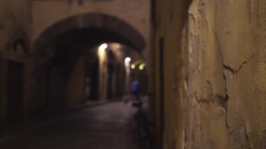 Avrupa 'nın odak noktası dışında küçük bir caddede dokulu duvarın kapatılması. Yıpranmış beton duvarın bulanık arka plan plakası ve düşük aydınlatılmış Avrupa sokak aralığı