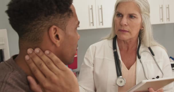 彼の首の苦痛についての若い黒人患者との成熟した白い医者の相談 首の損傷についての上級医師との魅力的なアフリカ系アメリカ人患者会議 — ストック動画