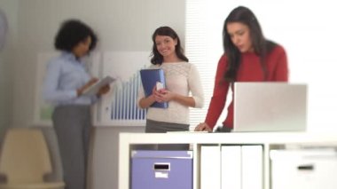 İş kadını kameraya gülümsüyor ve her iki tarafta da iş arkadaşları var.