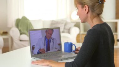 Yetişkin bir kadın bilgisayarında doktorla görüntülü konuşma yapıyor.