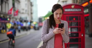 Çekici İspanyol kadın Londra 'da kayboldu. Latin kadın elinde cep telefonuyla şehir sokağında duruyor ve gideceği yeri arıyor. 4k