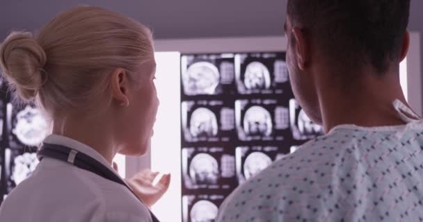 Крупный План Врача Объясняющего Рентгеновские Снимки Чёрному Пациенту — стоковое видео