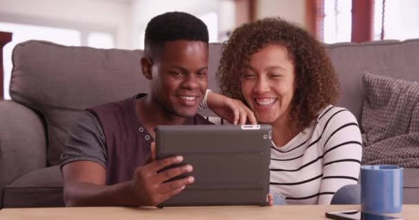 真正的千年黑人夫妇坐在地板上观看平板电脑上的视频 非裔美国人男人和女人在他们的垫子上看浏览 黑人男女在客厅里休息 — 图库视频影像