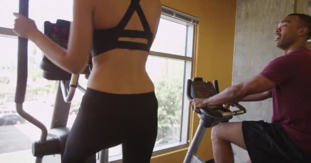 Black Man Working Out Stationary Cycle While Talking Hispanic Girlfriend — Stock Video