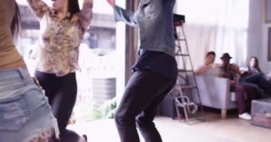 Oturma alanından garaj kapısına dans eden bir grup arkadaş partide eğleniyor.