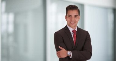 Mutlu gülümseyen genç İspanyol işadamı kollarını kavuşturup kameraya bakıyor. Yüzünde tebessüm olan iş adamının yanındaki boşluğu kopyala. 4k