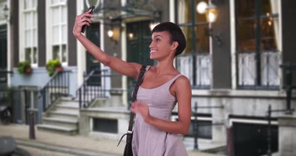 Жінка Вибухає Поцілунком Робить Фотографію Смартфоном Вулиці Амстердама Красива Чорношкіра — стокове відео