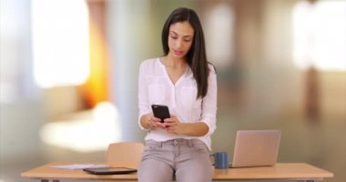Latin bir iş kadını, ofisinde akıllı telefonunu kullanır. İspanyol bir şirket çalışanının cep telefonuna bakması. 4k