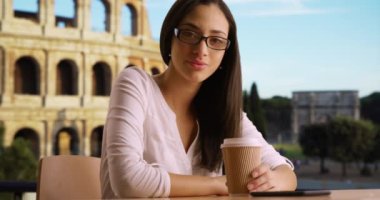 Roma kolezyumunun yanında elinde kahve fincanı tutan Latin bir kadının sıradan portresi. İspanyol turist dışarıda kameraya gülümsüyor. 4k