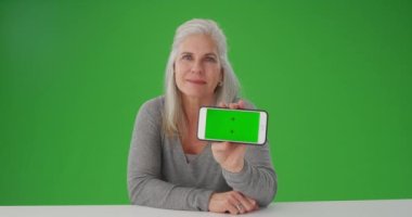 Güzel yaşlı kadın kameraya el bilgisayarı gösteriyor.