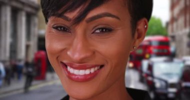 Londra 'da bir sokakta genç, güzel bir zenci kadın mutlulukla kameraya bakıyor. Afrikalı bin yıllık kadın Londra 'da seyahat ediyor, İngiltere sevinçle gülümsüyor. 4k