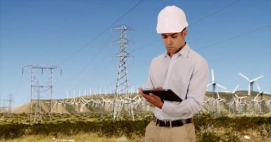 Latin Milenyum Mühendisi yenilenebilir enerji için rüzgar türbinlerini kontrol ediyor. İspanyol güç işçisi, başlık takıyor ve tablet bilgisayar kullanarak yel değirmenlerini kontrol ediyor. 4k