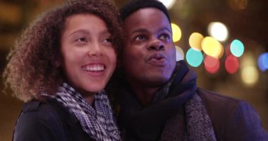 Genç Afrikalı Amerikalı çift şehrin gece hayatına hayran. Milenyum siyahi erkek ve kadın şehir ışıklarına bakın. 4k.