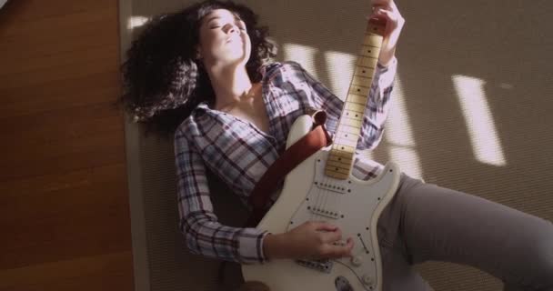 若い音楽の女性が床に横たわってギターを演奏 — ストック動画