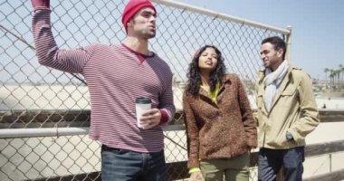 Bir grup etnik kökenli hippi arkadaş rıhtımda sohbet ediyor.