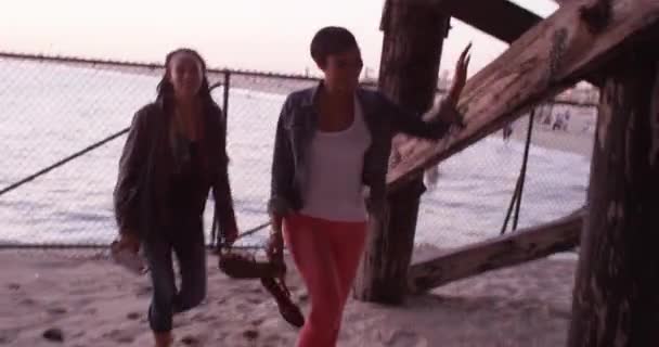在海滩的一天结束时 黑人女人最好的朋友跑到码头下大笑 — 图库视频影像
