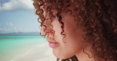 Siyah kız Karayip Okyanusu 'na bakıyor. Kıvırcık saçlı güzel Afro-Amerikan milenyum kadını ufka bakıyor. 4k.