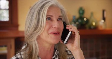 Güzel, olgun, beyaz bir kadın cep telefonuyla konuşuyor. Son sınıf öğrencisinin akıllı telefondaki sohbetinin keyfini çıkarırken..