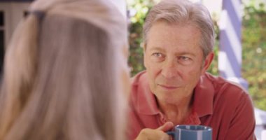 Orta yaşlı, beyaz erkek, bayan arkadaşıyla konuşuyor. Son sınıf öğrencisi, bayan arkadaşıyla sabah içkisini yudumlarken..