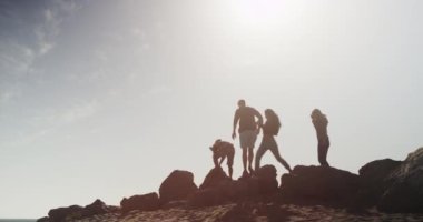 Plajda kayalar üzerinde yürüyen arkadaşlar