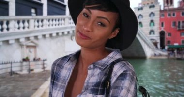 İtalya, Venedik 'te seyahat ederken güzel siyah kadın kameraya poz veriyor. Venedik 'teki Rialto Köprüsü' nün yanında duran modern siyahi kadın gülümseyen kameraya bakıyor. 4k