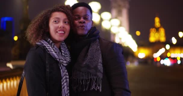 夜にポンアレクサンドル2世橋の上に立つ幸せな観光客のカップル アフリカ系アメリカ人の夫婦は 夜にパリで新婚旅行を楽しんでいます — ストック動画