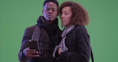 Genç Afrikalı Amerikalı çift yeşil ekranda akıllı telefonları olan bir taksi çağırıyorlar. Anahtar ya da birleşik olmak üzere yeşil ekranda.