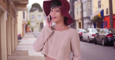 Sarkık şapkalı mutlu zenci kadın San Francisco 'da akıllı telefondan konuşuyor. 20 'li yaşlarda cep telefonu kullanan modaya uygun bir kız..