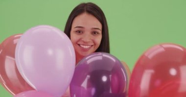 İspanyol kız yeşil ekranda bir sürü renkli balonla oynuyor. Anahtar ya da birleşik olmak üzere yeşil ekranda.